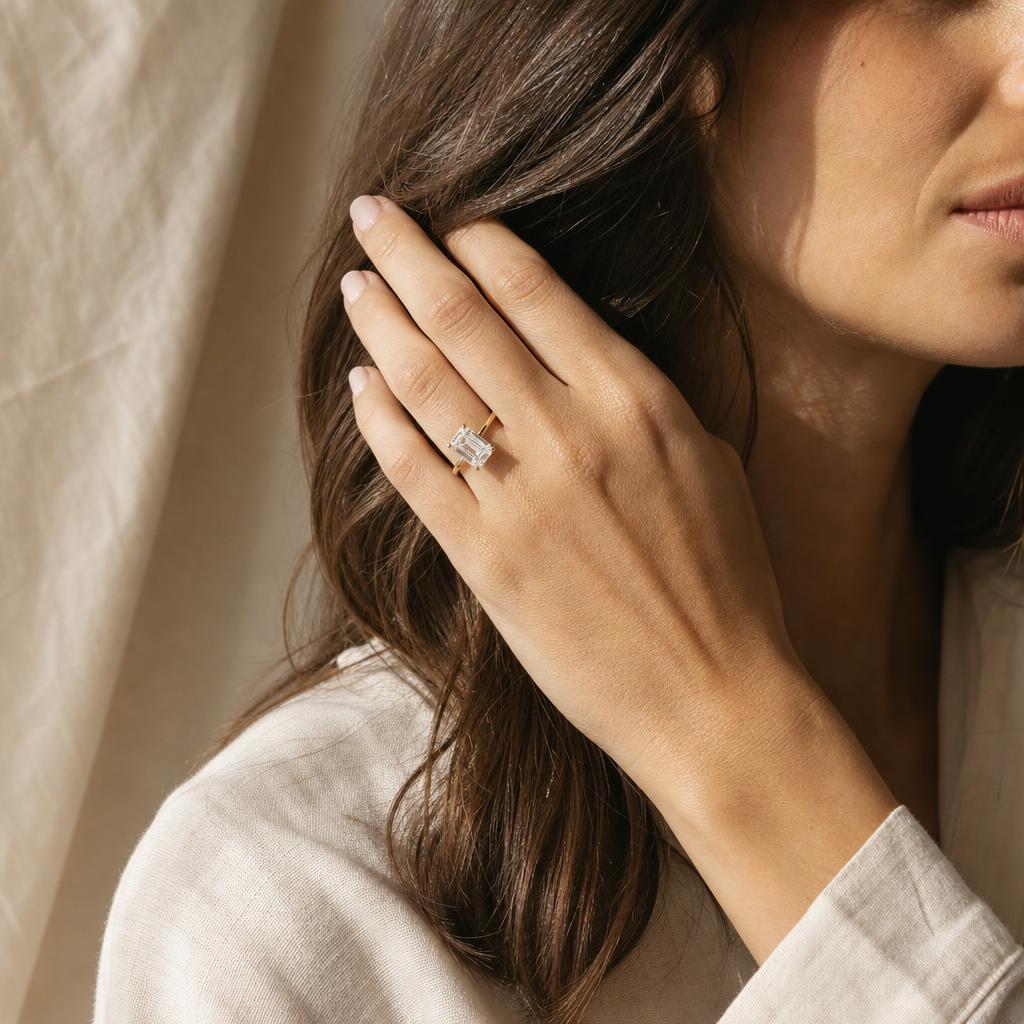 Woman wearing an emerald-cut diamond solitaire ring in 18k yellow gold