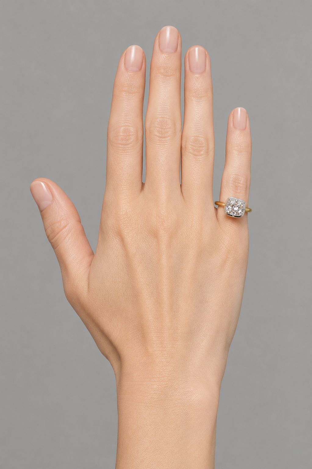 The RW pinky dome ring worn on the little finger, cushion-cut diamond in a white gold bezel on an 18k yellow gold band