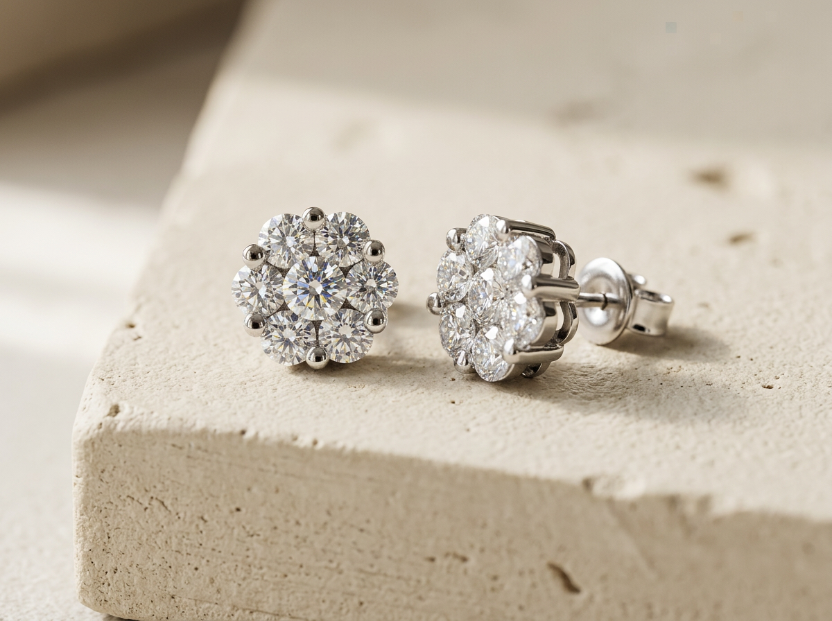 Pair of RW Daisy diamond stud earrings, seven round brilliant diamonds in a 14k white gold cluster, on warm cream textured concrete