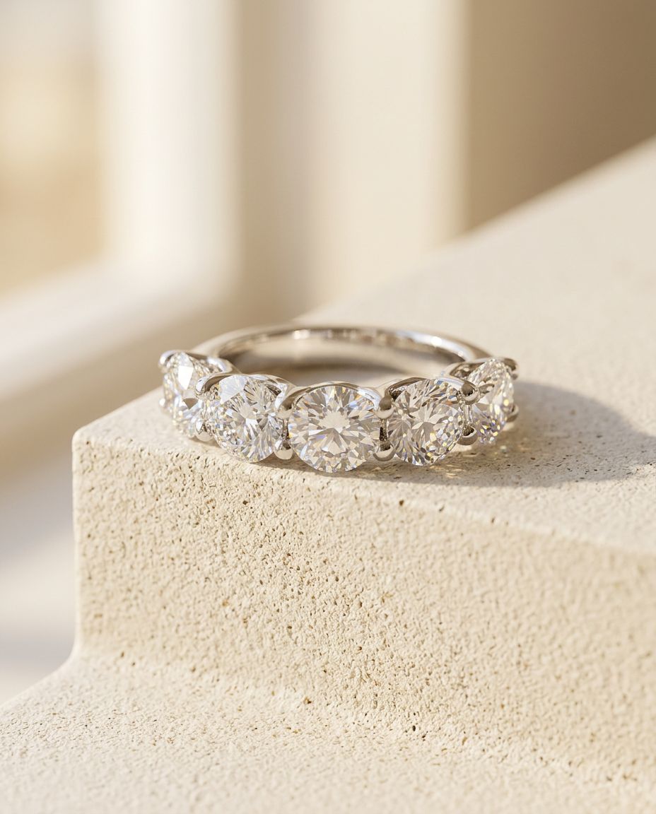 Front view of the five stone diamond band resting on a pale micro-cement ledge